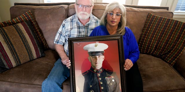Joey and Paula Reed pose for a photo with a portrait of their son, Marine veteran and Russian prisoner Trevor Reed, at their home in Fort Worth, Texas, Feb. 15, 2022.