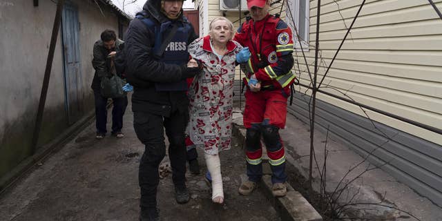 Associated Press photographer Evgeniy Maloletka helps a paramedic to transport a woman injured during shelling in Mariupol, eastern Ukraine, March 2, 2022.
