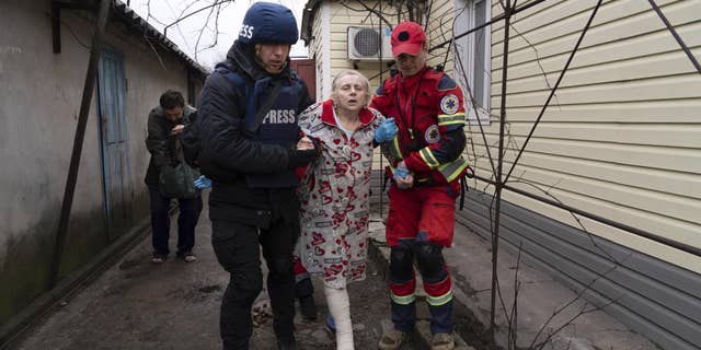 Associated Press photographer Evgeniy Maloletka helps a paramedic to transport a woman injured during shelling in Mariupol, eastern Ukraine, March 2, 2022.