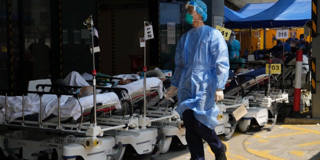 Patients in hospital beds wait in a temporary holding area.