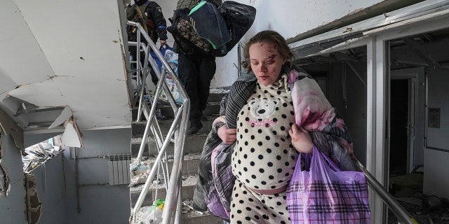 An injured pregnant woman walks downstairs in the damaged by shelling maternity hospital in Mariupol, Ukraine.