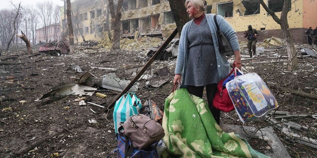 Une femme marche devant la maternité endommagée par les bombardements à Marioupol, en Ukraine, le mercredi 9 mars 2022. Une attaque russe a gravement endommagé une maternité dans la ville portuaire assiégée de Marioupol, selon des responsables ukrainiens.