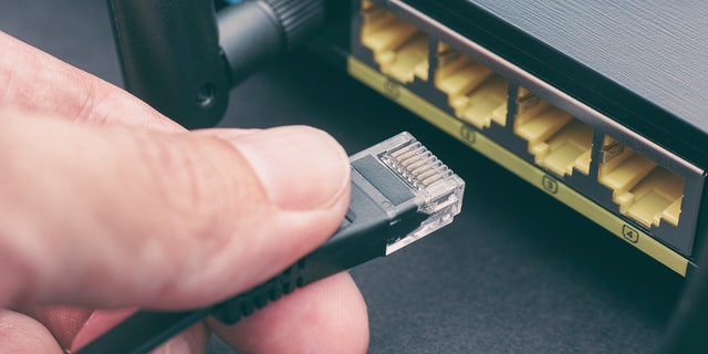 Person plugging cable into wireless router. close up.