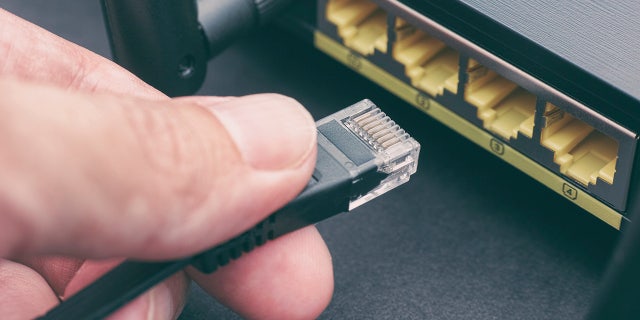 Person plugging cable into wireless router. close up.