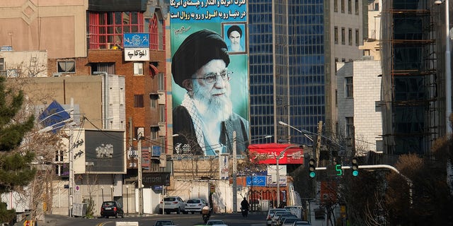 A huge mural of Ayatollah Seyyed Ali Khamenei, the supreme leader of Iran, painted next to a smaller one by Ayatollah Ruhollah Khomeini (R) seen in Tehran, Iran.  It reads the message on the wall "America's power, influence and dignity in the world are about the fall and extermination" and at the top of the building you can read another slogan "We are standing until the end".