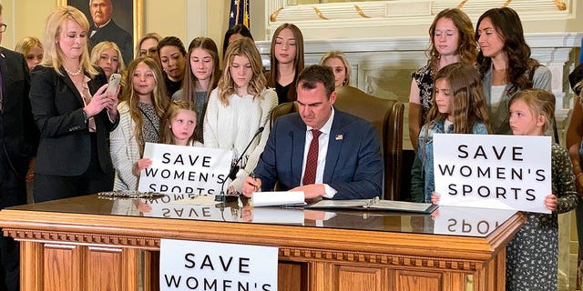 Oklahoma Gov. Kevin Stitt signs a bill in Oklahoma City on Wednesday, March 30, 2022, that prevents transgender girls and women from competing on female sports teams. Stitt signed the bill flanked by more than a dozen young female athletes, including his eighth-grade daughter Piper. (WHD Photo/Sean Murphy)