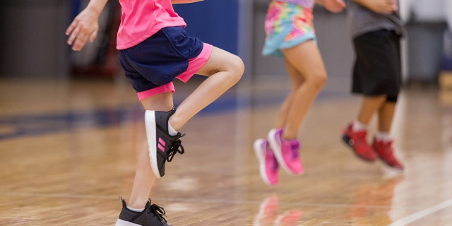 Unrecognizable elementary students warm up before PE class.