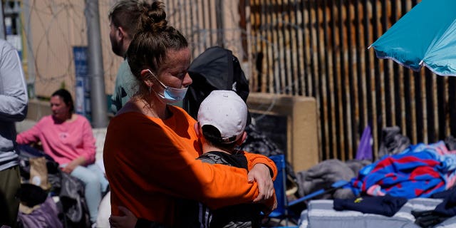 A Russian woman hugs her son as they wait near the San Ysidro Port of Entry leading into the United States on March 17, 2022.