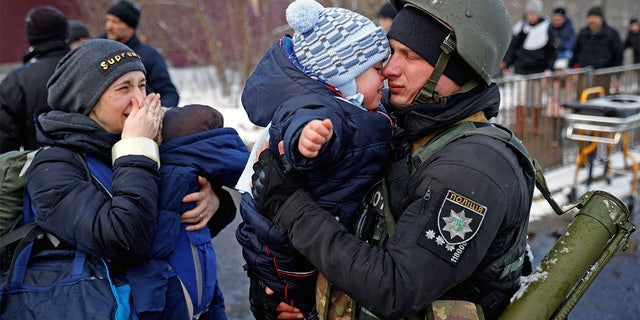 A police officer says goodbye to his son as his family flees from advancing Russian troops as Russia's attack on Ukraine continues in the town of Irpin outside Kyiv, Ukraine, March 8, 2022. 