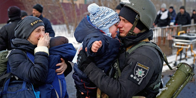 A police officer says goodbye to his son as his family flees from advancing Russian troops as Russia's attack on Ukraine continues in the town of Irpin outside Kyiv, Ukraine, March 8, 2022. 