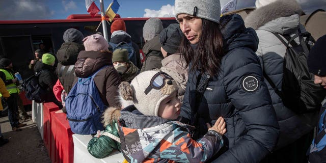 A Polish soldier holds a baby as refugees fleeing war in neighboring Ukraine arrive at the Medyka crossing border, Poland, Thursday, March 10, 2022.