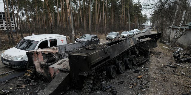 Cars drive past a destroyed Russian tank as a convoy of vehicles evacuating civilians leaves Irpin, on the outskirts of Kyiv, Ukraine, March 9, 2022. 