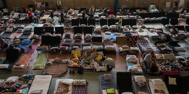 Las personas que huyeron de la guerra en Ucrania descansan dentro de un estadio deportivo cubierto que se utiliza como centro de refugiados, en el pueblo de Medyka, un cruce fronterizo entre Polonia y Ucrania, el 15 de marzo de 2022. 