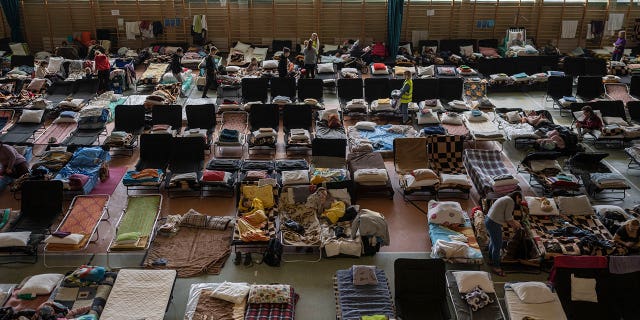 Las personas que huyeron de la guerra en Ucrania descansan dentro de un estadio deportivo cubierto que se utiliza como centro de refugiados, en el pueblo de Medyka, un cruce fronterizo entre Polonia y Ucrania, el 15 de marzo de 2022.