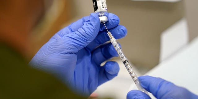 A health care worker fills a syringe with the Pfizer COVID-19 vaccine at Jackson Memorial Hospital on Oct. 5, 2021, in Miami.