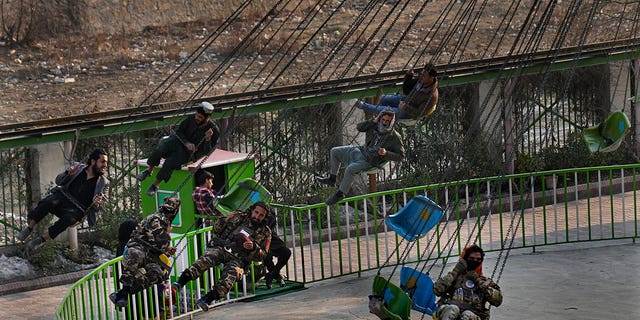Taliban fighters with other Afghan men, ride a swing at an amusement park, in Kabul, Afghanistan, Feb. 18, 2022.