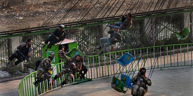 Taliban fighters with other Afghan men, ride a swing at an amusement park, in Kabul, Afghanistan, Feb. 18, 2022.