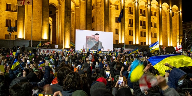 A speech by Ukrainian President Volodymyr Zelenskyy is streamed live on a big screen to a crowd outside the Parliament building in Tbilisi, Georgia, March 4, 2022.