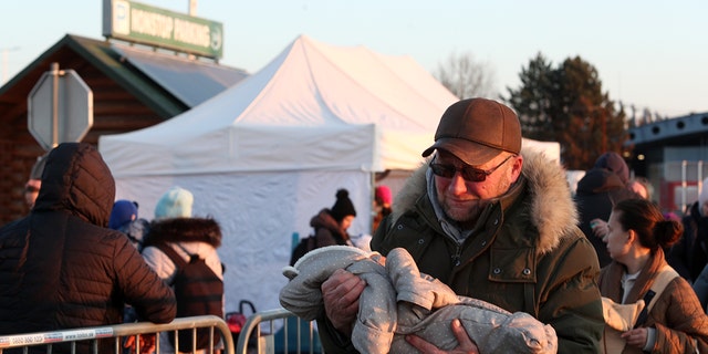 These people are trying to escape harm in Ukraine; here, a man is shown carrying a young child at a refugee camp. 