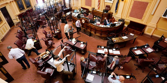 Susan Schaar, center, clerk of the Senate, helps remove COVID barriers after the session at the Capitol on Monday, Feb. 28, 2022, in Richmond, Va. The barriers had been since last year's special session.