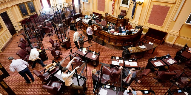 Susan Schaar, center, clerk of the Senate, helps remove COVID barriers after the session at the Capitol on Monday, Feb. 28, 2022, in Richmond, Va. The barriers had been since last year's special session.