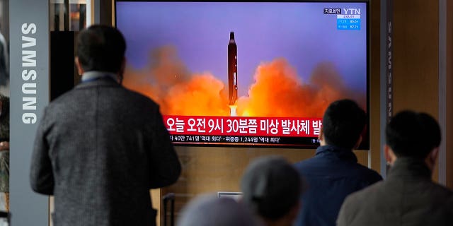 People watch a TV screen showing a news program reporting about North Korea's missile with file footage, at a train station in Seoul, South Korea, Wednesday, March 16, 2022.