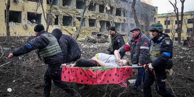 Ukrainian emergency employees and volunteers carry an injured pregnant woman from the damaged by shelling maternity hospital in Mariupol, Ukraine.