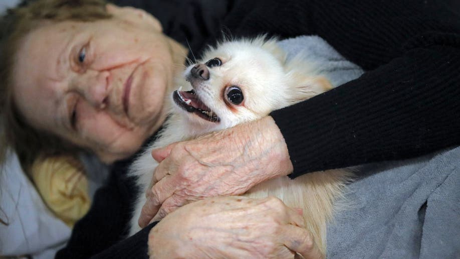 Woman cuddles with dog in refuge shelter