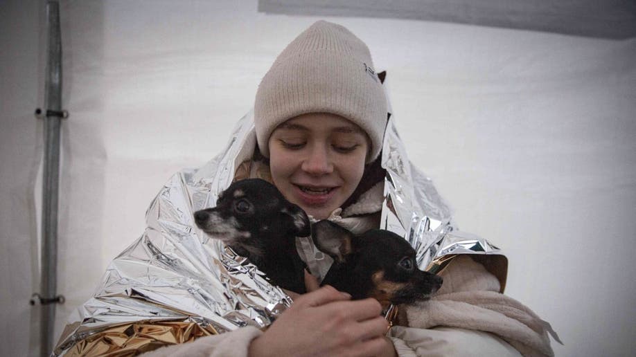 Woman hugs dogs in warming blanket