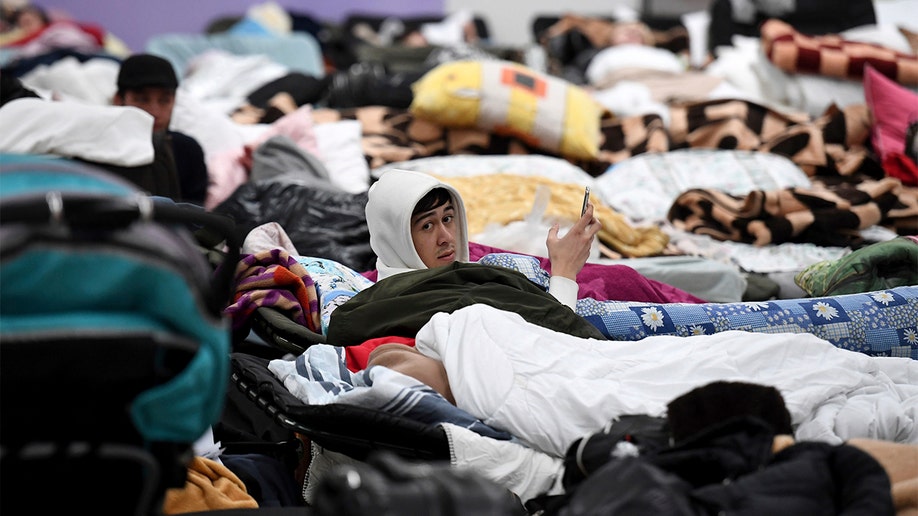 A man checks his mobile phone as he looks up from his sleeping cot, at a reception center for displaced persons from Ukraine, at the Ukrainian-Polish border crossing in Korczowa, Poland, Saturday, March 5, 2022. U.S. Secretary of State Antony Blinken toured the center on Saturday with Polish officials. (Olivier Douliery, Pool Photo via WHD)