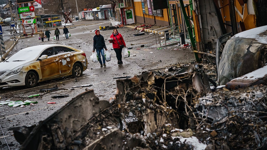 Residents carrying supplies walk back from the direction of Bucha, amid the debris of battle with Russian forces, on the outskirts of Irpin, Ukraine, Tuesday, March 1, 2022.