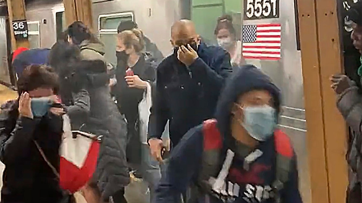In this photo from social media video, passengers run from a subway car in a station in the Brooklyn borough of New York, Tuesday, April 12, 2022. (Will B. Wylde via AP)