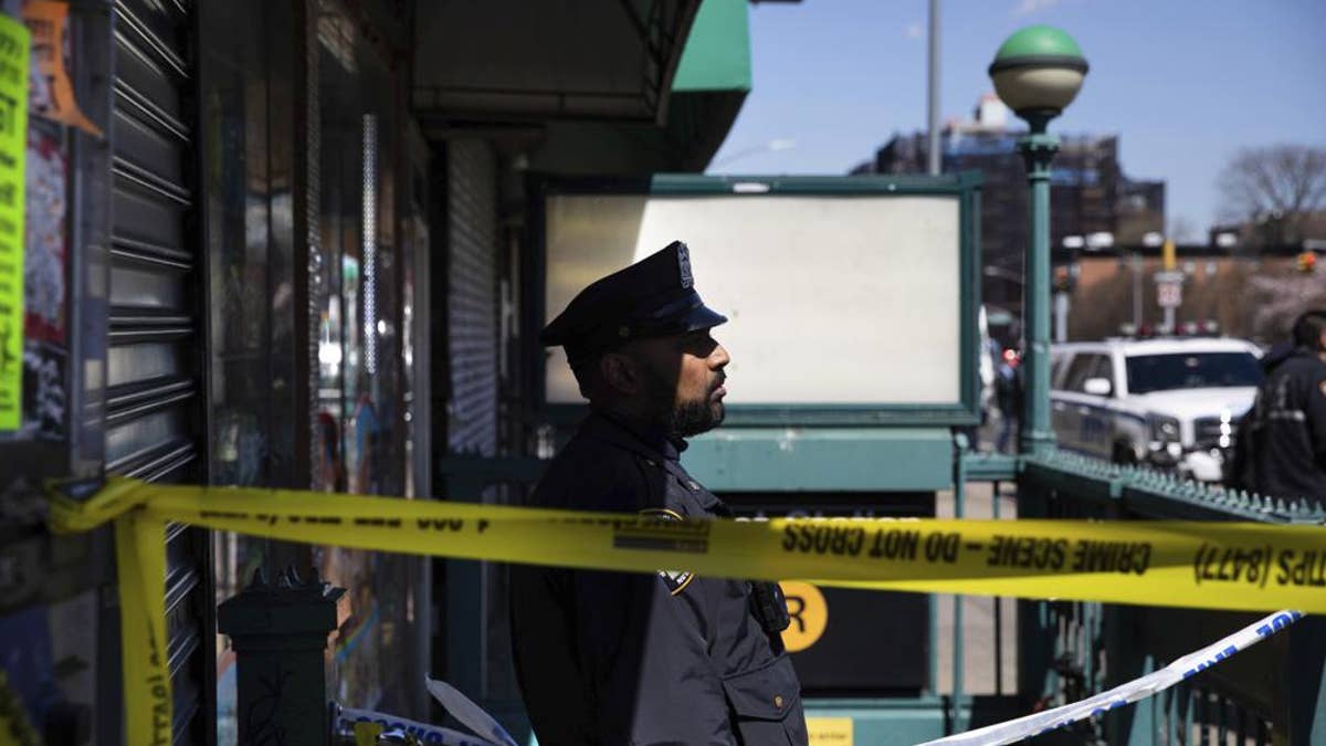 A police officer stands watch at the entrance of 36th Street Station after multiple people were shot on a subway train, Tuesday, April 12, 2022, in the Brooklyn borough of New York.