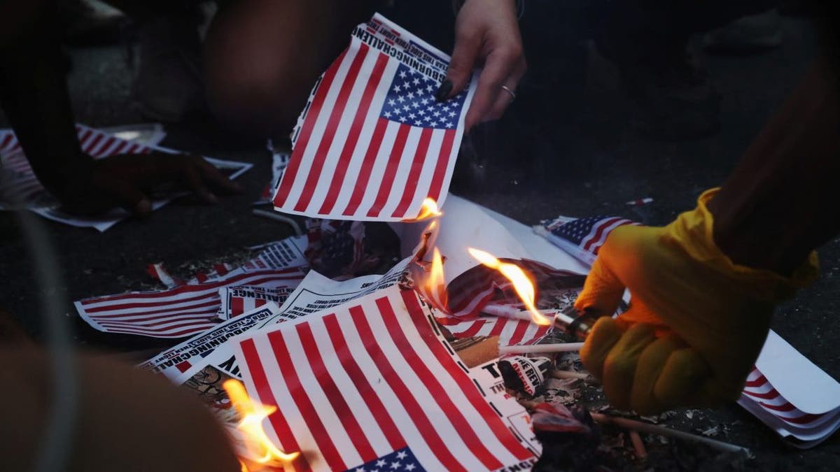 A group of protesters burn American flags and leaflets with the flag, even as other protesters disagreed with the act, during a protest against racial inequality and police violence near Black Lives Matter Plaza, during Fourth of July holiday, in Washington, U.S., July 4, 2020.  REUTERS/Leah Millis