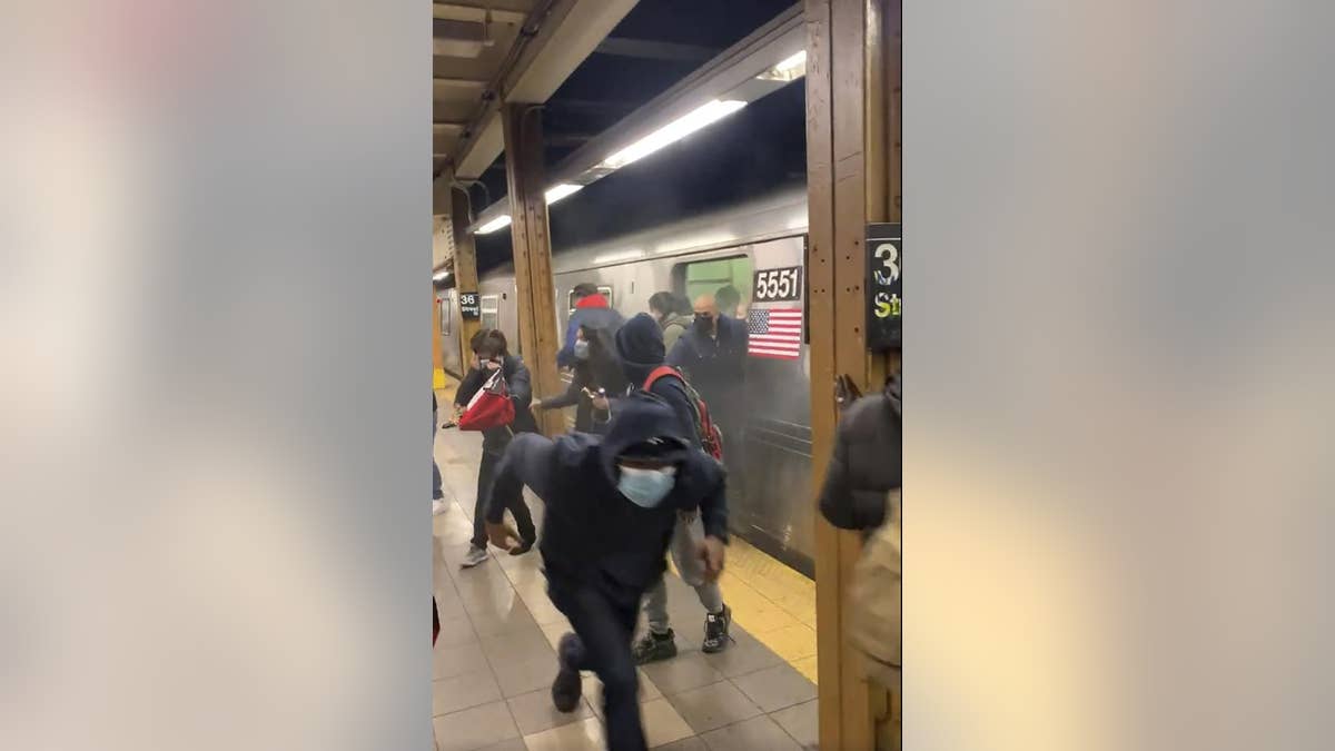 In this photo from social media video, passengers run from a subway car in a station in the Brooklyn borough of New York, Tuesday, April 12, 2022.