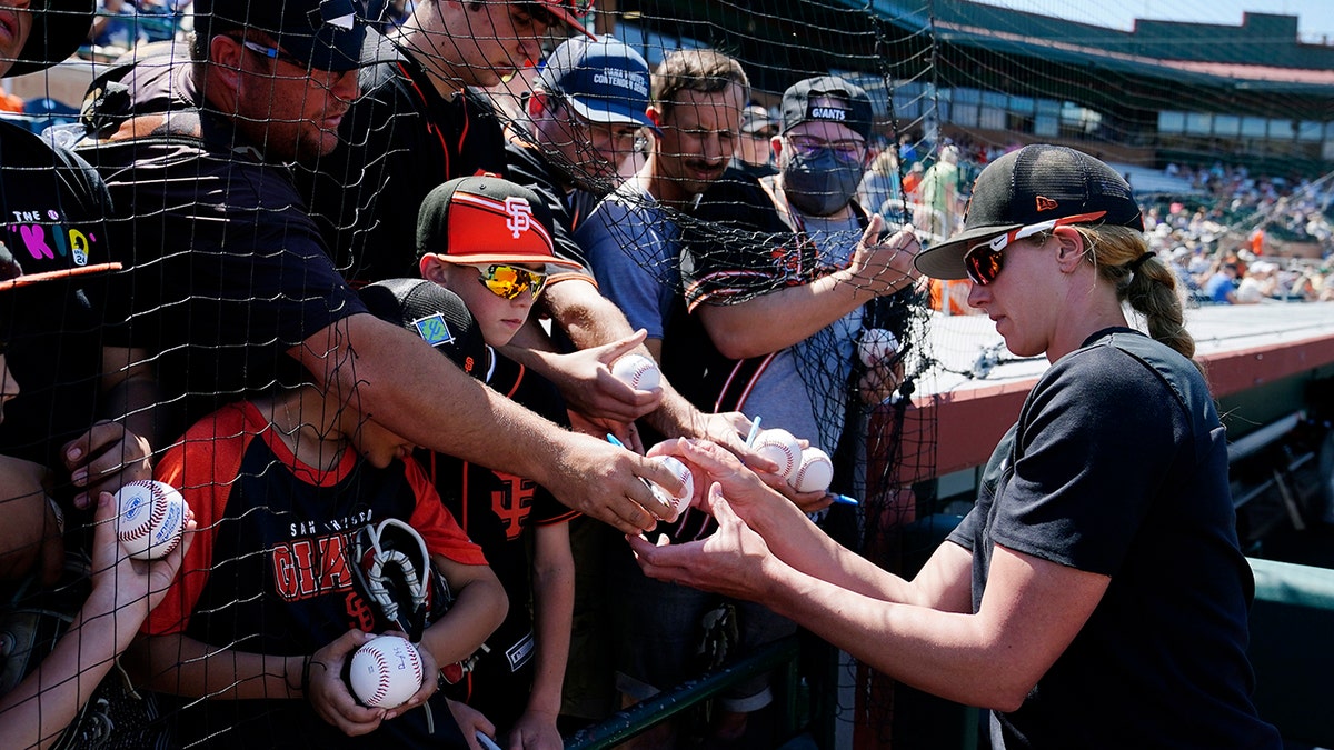 San Francisco Giants assistant coach Alyssa Nakken signs autographs for fans prior to a spring training baseball game against the Colorado Rockies Thursday, March 31, 2022, in Scottsdale, Ariz.