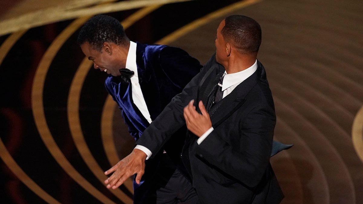 Will Smith, right, hits presenter Chris Rock on stage while presenting the award for best documentary feature at the Oscars on Sunday, March 27, 2022, at the Dolby Theater in Los Angeles. 