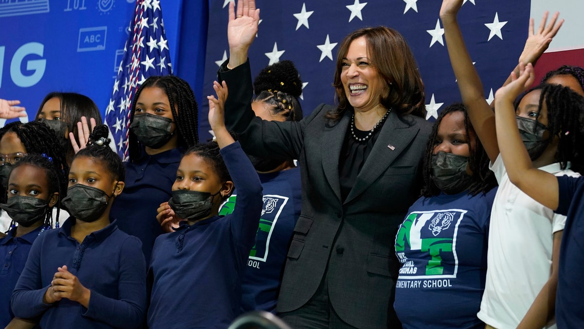 Vice President Kamala Harris poses maskless with masked students.