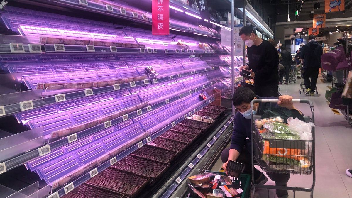 Customers look through empty shelves at a supermarket in Shanghai, China, on March 30, 2022. 