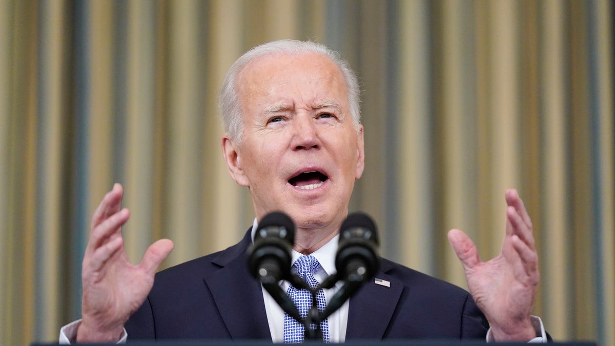 President Joe Biden gestures in a suit behind a podium