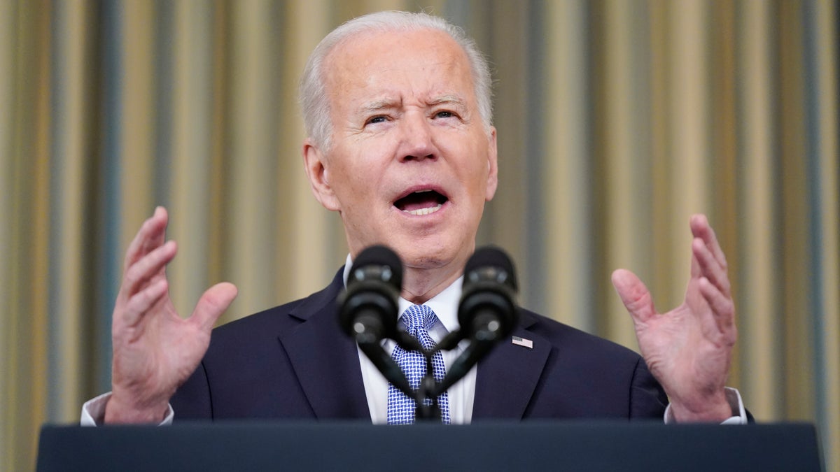 President Joe Biden gestures in a suit behind a podium