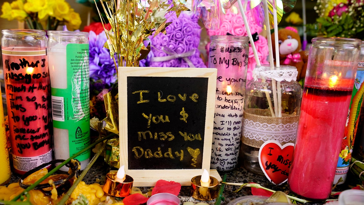 A message left for one of the victims of a recent mass shooting sits among flowers and candles at a memorial in Sacramento, Calif., Saturday, April 9, 2022.