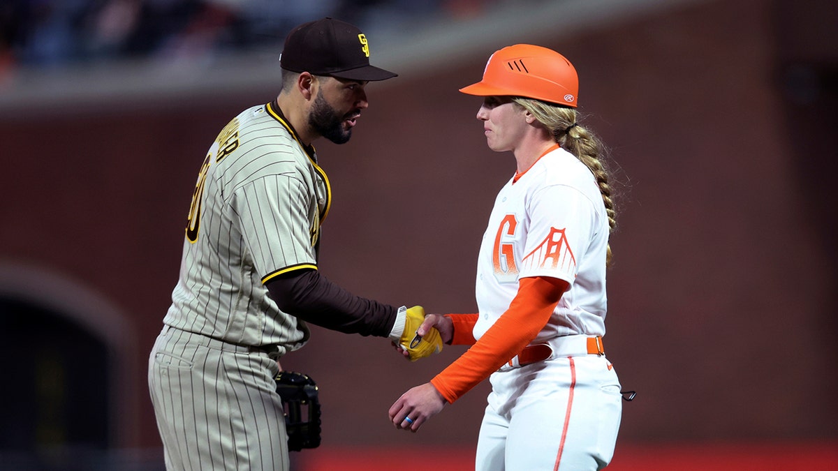 San Diego Padres first baseman Eric Hosmer, left, shakes hands with San Francisco Giants first base coach Alyssa Nakken during the third inning of a baseball game in San Francisco, Tuesday, April 12, 2022.