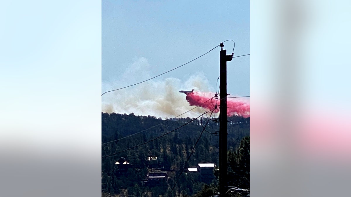 This photo provided by the Village of Ruidoso shows a fire fighting air tanker dropping fire retardant across the mountains near the Village of Ruidoso, N.M., on Wednesday, April 13, 2022. 