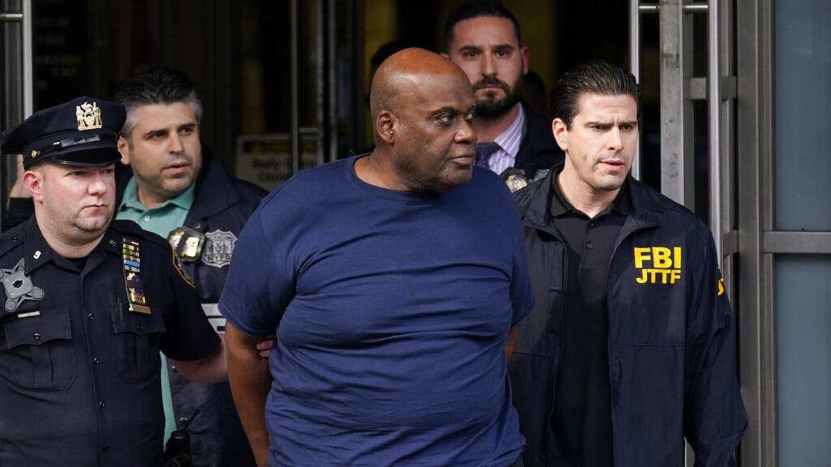 New York City Police, left, and law enforcement officials lead subway shooting suspect Frank R. James, 62, center, away from a police station, in New York, Wednesday, April 13, 2022. The man accused of shooting multiple people on a Brooklyn subway train was arrested Wednesday and charged with a federal terrorism offense.