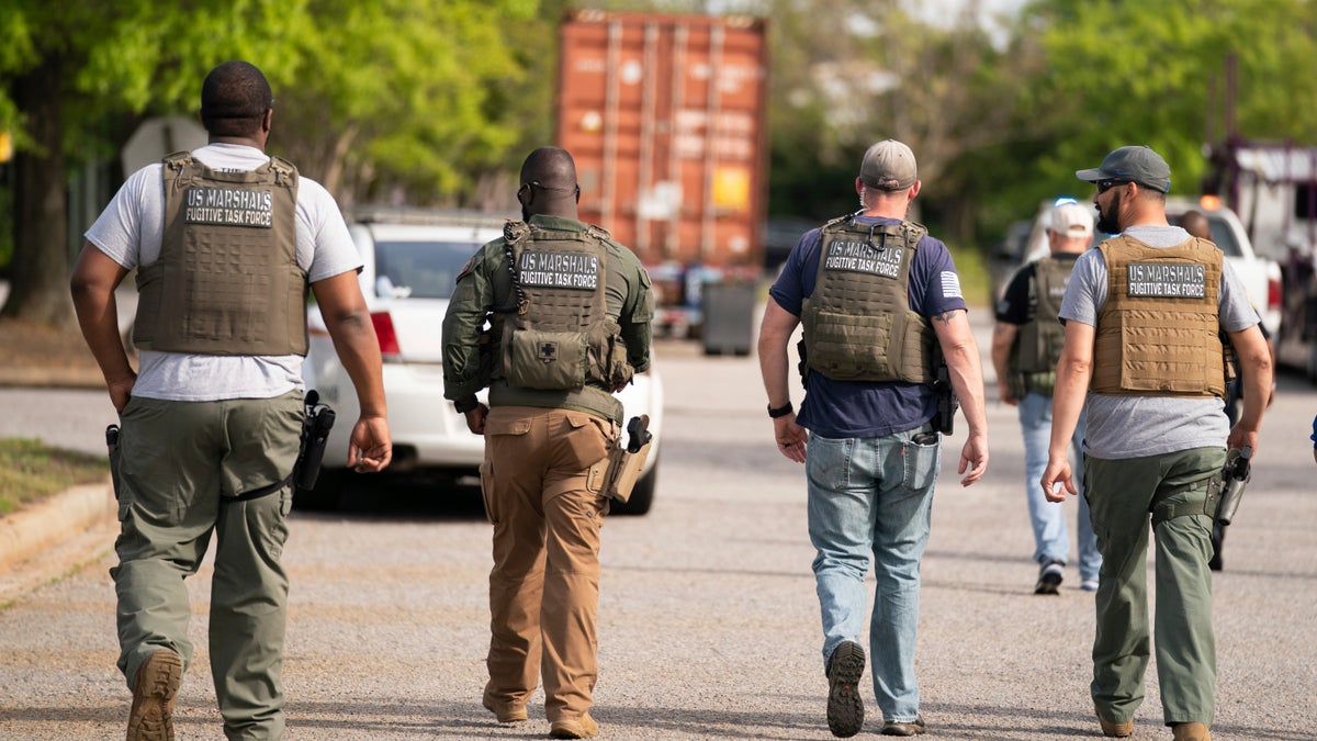 Members of the U.S. Marshals fugitive task force walk down a street near Columbiana Centre mall in Columbia, S.C., following a shooting, Saturday, April 16, 2022.