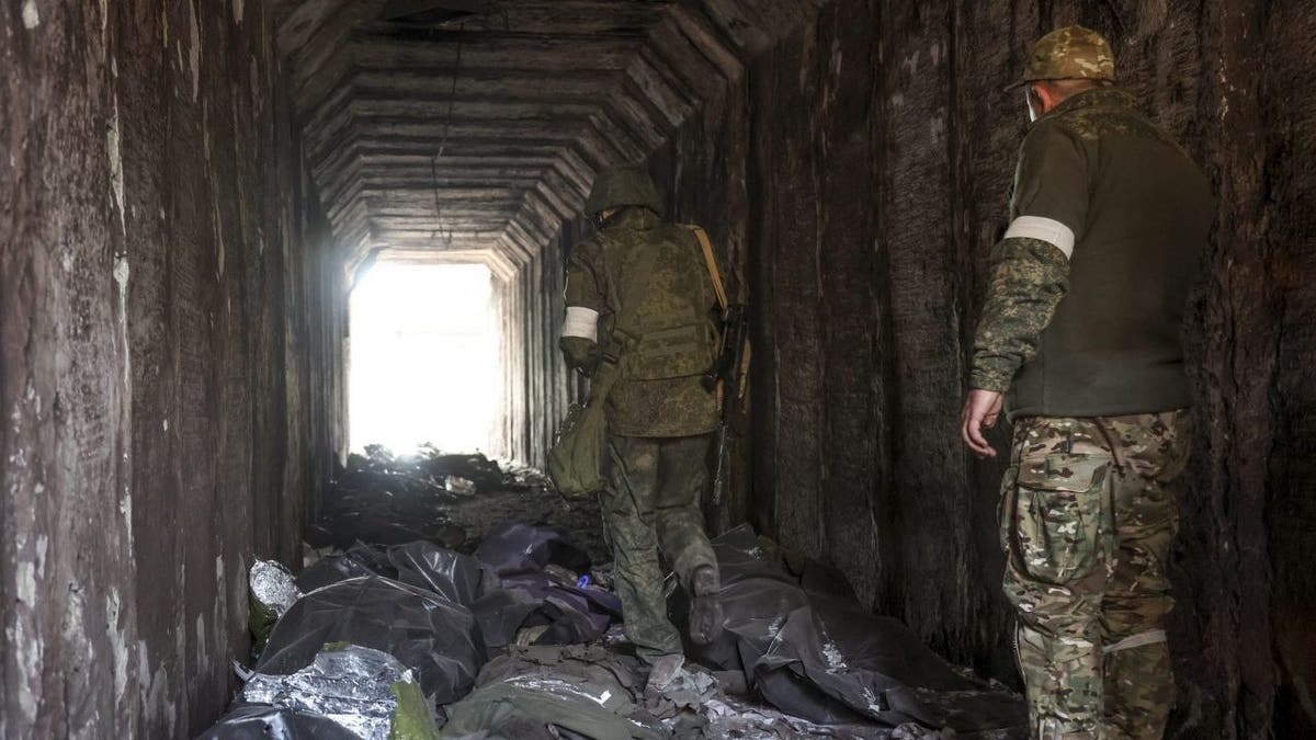 Servicemen of the Donetsk People's Republic militia look at bodies of Ukrainian soldiers placed in plastic bags in a tunnel, part of the Illich Iron &amp;amp; Steel Works Metallurgical Plant, the second largest metallurgical enterprise in Ukraine, in an area controlled by Russian-backed separatist forces in Mariupol, Ukraine, Monday, April 18, 2022. Mariupol, a strategic port on the Sea of Azov, has been besieged by Russian troops and forces from self-proclaimed separatist areas in eastern Ukraine for more than six weeks. 