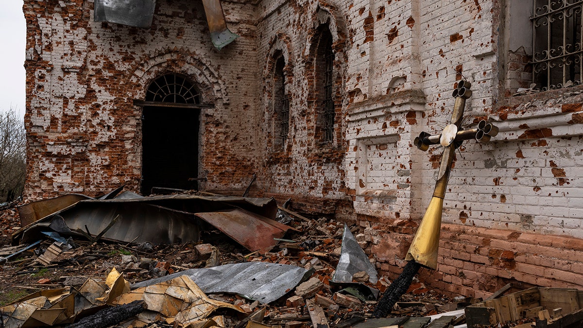 A metal cross that used to be on the top of the dome stands outside of the damaged church in Lukashivka, in northern Ukraine, on Friday, April 22, 2022.