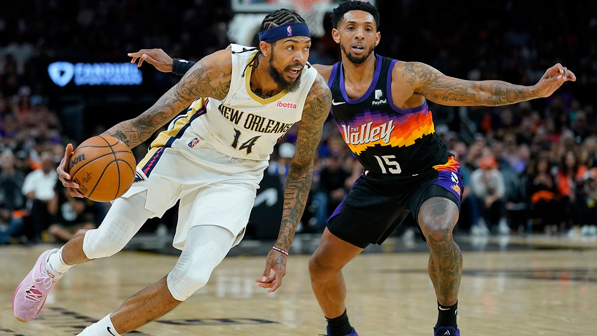 New Orleans Pelicans forward Brandon Ingram (14) dries as Phoenix Suns guard Cameron Payne (15) defends during the second half of Game 2 of an NBA basketball first-round playoff series, Tuesday, April 19, 2022, in Phoenix.