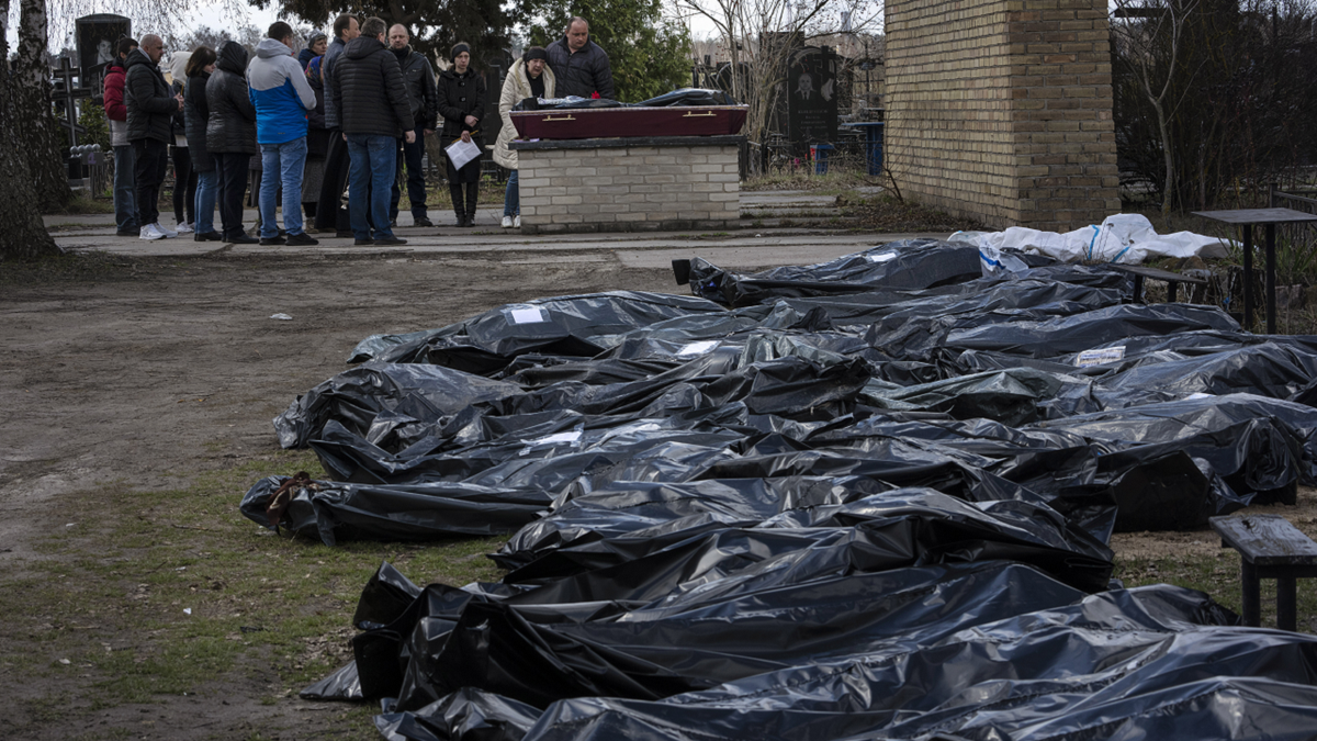 A family mourns a relative killed during the war with Russia, as dozens of black bags containing more bodies of victims are seen strewn across the graveyard in the cemetery in Bucha, in the outskirts of Kyiv, Ukraine, on Monday.